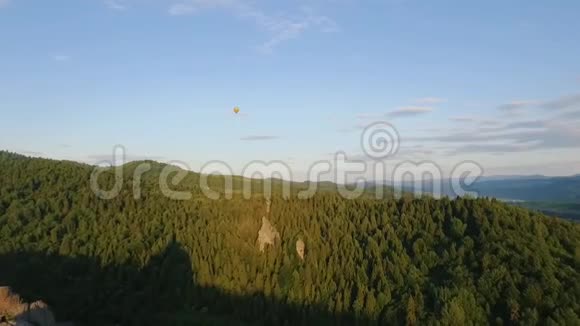 热空气气球在岩石附近的山脉中飞过天空视频的预览图
