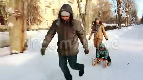 一家人正在给他们的儿子打雪橇视频的预览图