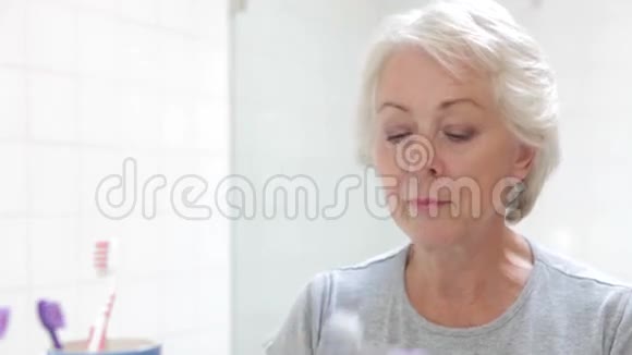 高级妇女反映在浴室镜子刷牙视频的预览图