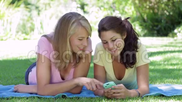 两个少女躺在花园里读短信视频的预览图