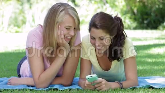 两个少女躺在花园里读短信视频的预览图