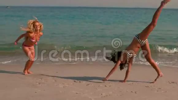 快乐的女孩在海滩上做一个手推车视频的预览图