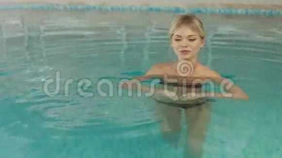 金发碧眼的女孩漂浮在游泳池里视频的预览图
