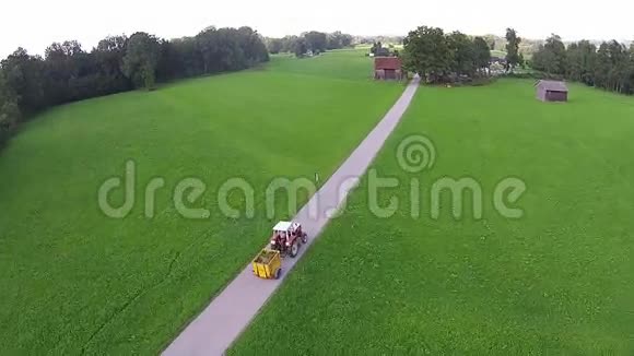拖拉机在田野上开着绿色的草地阳光明媚视频的预览图