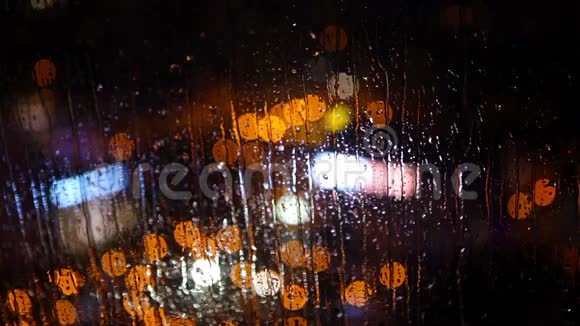 模糊的夜晚城市灯在雨中透过一个潮湿的玻璃与流水滴巴统格鲁吉亚视频的预览图