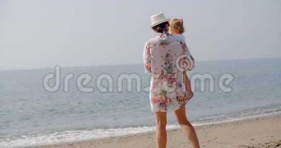 女子站在沙滩上抱着小孩视频的预览图