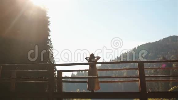 美丽的少女若虫站在喀尔巴阡山河上的木桥上欣赏日落视频的预览图