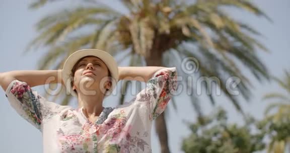有棕榈树的沙滩上张开双臂的女人视频的预览图