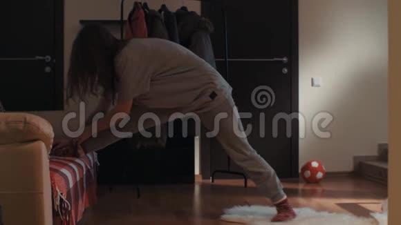 客厅里年轻的黑发女孩在地毯上滑倒不小心弄裂视频的预览图