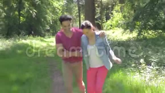 浪漫情侣一起沿着夏日的林地小径漫步视频的预览图