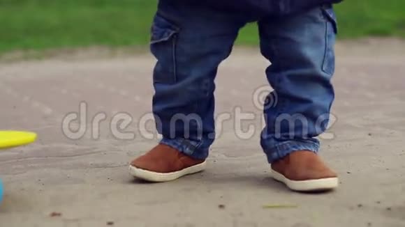 可爱的小孩子穿着蓝色牛仔裤走在滑板附近婴儿腿视频的预览图