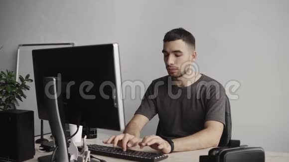 年轻的商人学生或自由职业者穿着衬衫坐在电脑旁在桌子旁敲键盘视频的预览图