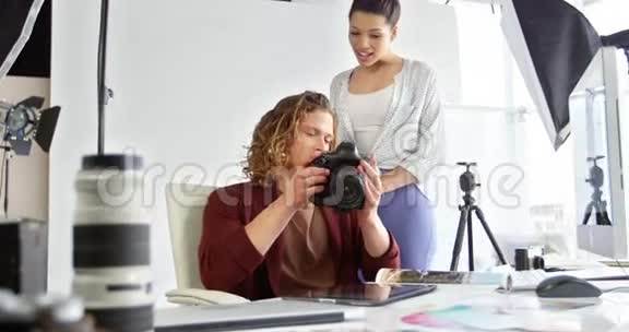 摄影师在数码相机上看照片视频的预览图
