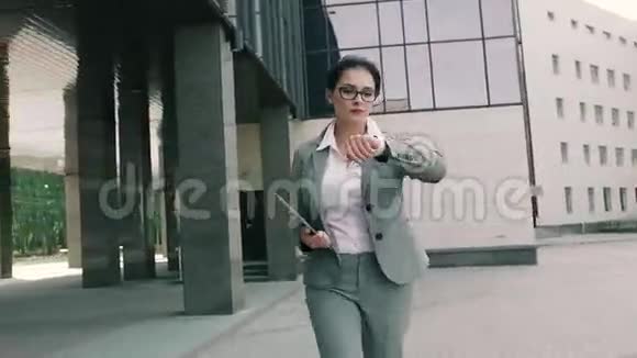年轻的女商人走到办公楼前视频的预览图