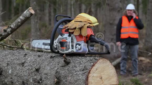 带手套的电锯背景伐木工人在讲智能手机视频的预览图