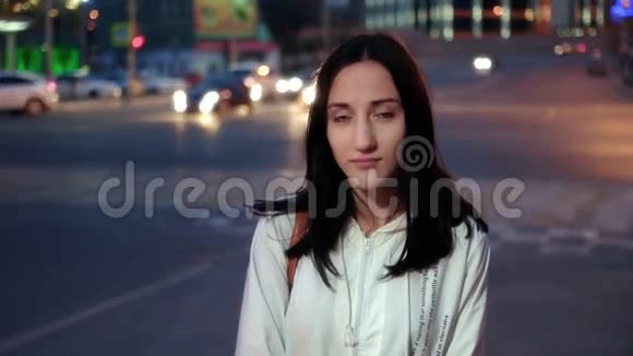 城市中的年轻快乐女性夜晚在模糊的车灯背景上严肃的面部肖像视频的预览图