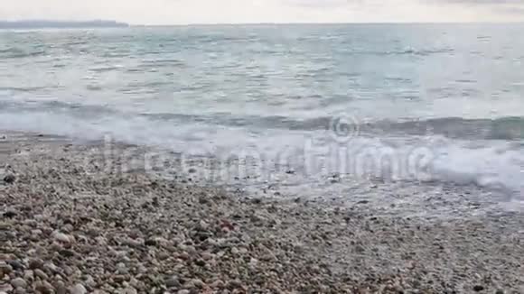 白天从海滩鹅卵石海滩蔚蓝的大海起泡的海浪中欣赏全景视频的预览图