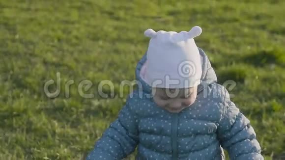 可爱的蹒跚学步的女孩在春天公园的草地上散步视频的预览图