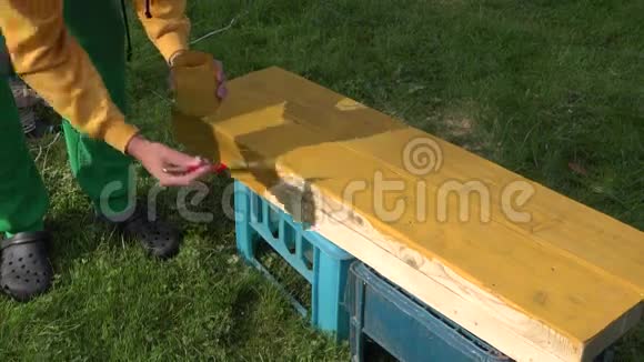 男画家手拿刷子和罐子用油漆画黄色的木制表面4K视频的预览图