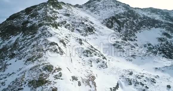在冬天的雪山上有登山滑雪者在登山雪覆盖了山顶视频的预览图