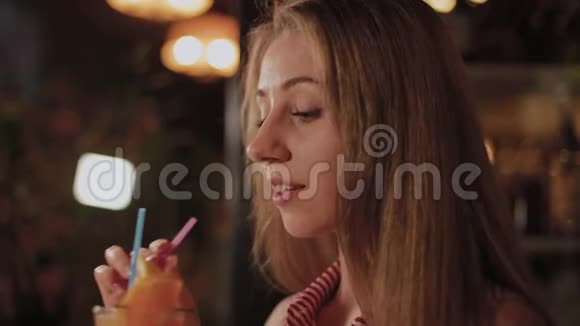 美丽的女孩与一个美丽的新鲜明亮的晚上鸡尾酒在咖啡馆视频的预览图