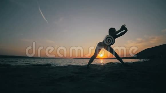 身材苗条的小女孩在日出时在海上从事体操无法辨认的轮廓视频的预览图