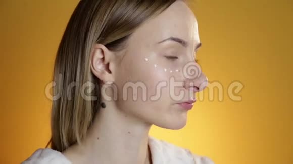 漂亮的模特把面霜放在黄色背景上视频的预览图