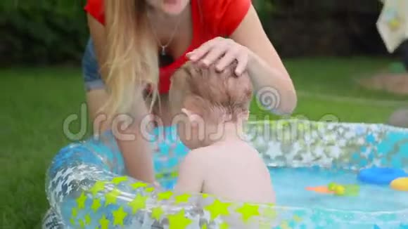 快乐微笑的小男孩在后院的充气游泳池里和妈妈玩耍视频的预览图