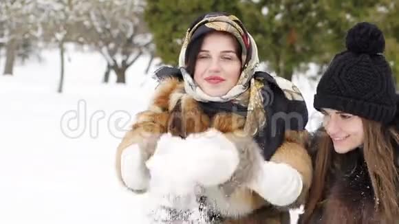 两个快乐的女孩微笑着在公园里吐雪慢慢地视频的预览图