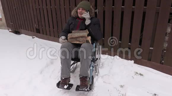 坐在轮椅上的残疾人拿着木柴在电话中交谈视频的预览图