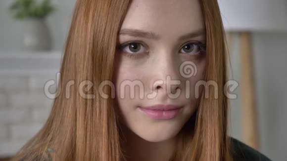 年轻的红发女孩博客作者肖像看着相机严肃的脸微笑美丽的眼睛看起来60英尺视频的预览图