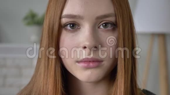 年轻的红发女孩博客作者肖像看着相机严肃的脸微笑美丽的眼睛看起来60英尺视频的预览图