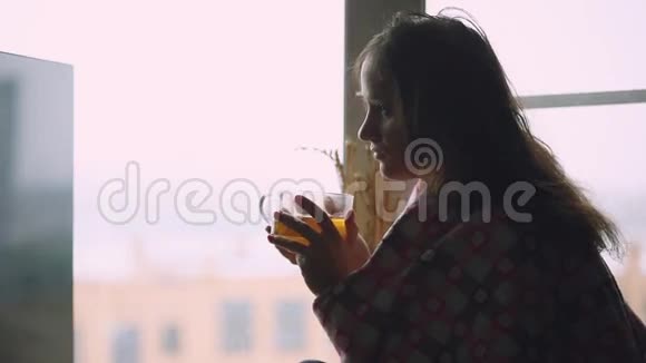 坐在窗台上喝茶的沮丧悲伤的病妇坐在窗台上地望着窗户1920x1080视频的预览图