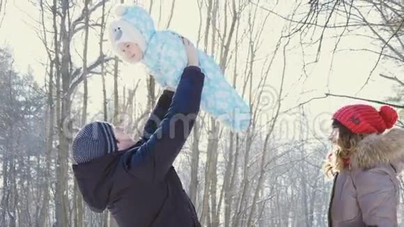 父亲把他的儿子扔到冬天公园的天空中慢动作视频的预览图