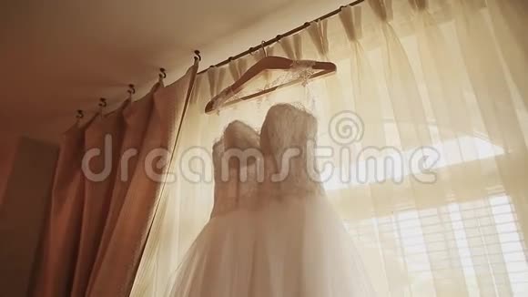 漂亮的白色豪华婚纱挂在窗户的背景上视频的预览图