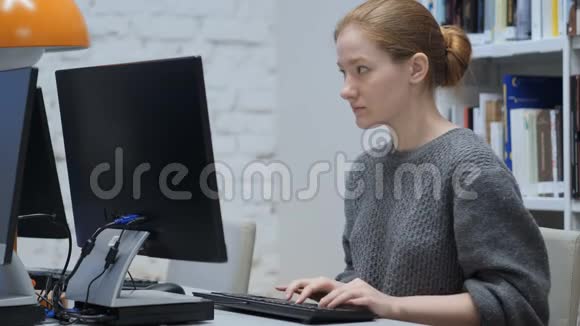 红发妇女在办公室用电脑工作视频的预览图
