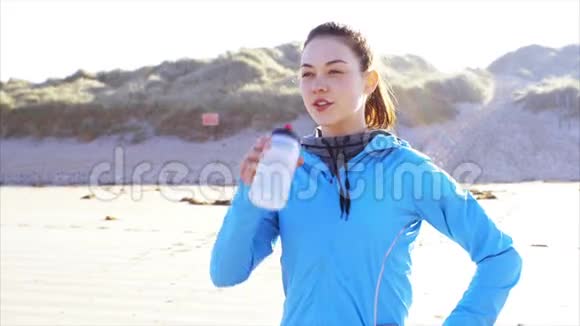 在海滩上观看健康女性饮用水的镜头视频的预览图