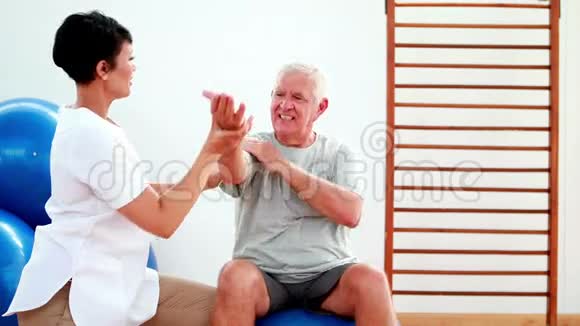 微笑理疗师帮助老年病人伸展手臂视频的预览图