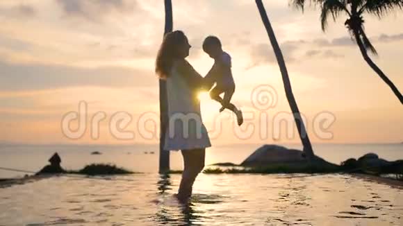 日落时带着孩子在海滩上散步和玩耍的女孩家庭休闲视频的预览图
