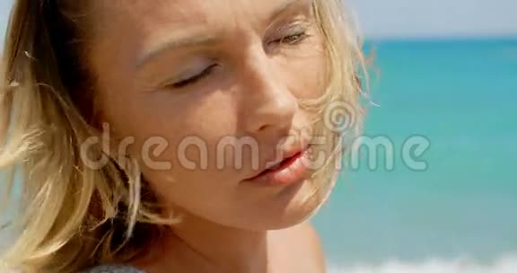 金发女人在沙滩上享受温暖的阳光视频的预览图