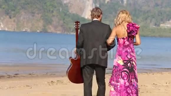 吉他手和金发女孩走向大海指向天空视频的预览图