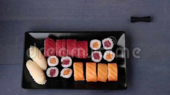 寿司将黑菜和卷在黑色盘子上上面有筷子酱油芥末和生姜平躺式视频的预览图