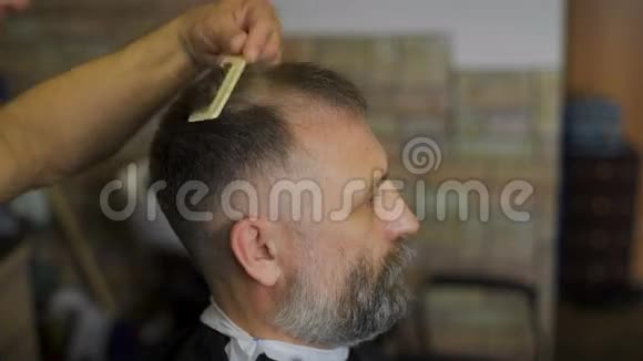 美发师在专业美发沙龙的皇冠客户上用剪刀剪头发一个头发花白的男人视频的预览图