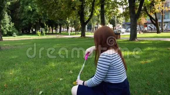 红发女孩在公园里吹肥皂泡视频的预览图