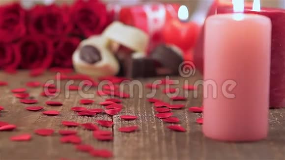 红玫瑰和巧克力糖果木头上有蜡烛视频的预览图