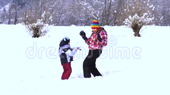 妈妈和小儿子在雪地里玩得很开心他们笑着掉进雪里视频的预览图