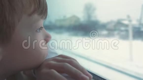 男孩正在窗户里寻找冬天的风景视频的预览图