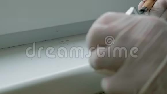 一个戴着橡胶手套的人用刮刀将窗台复原用浆糊涂在破损的地方视频的预览图