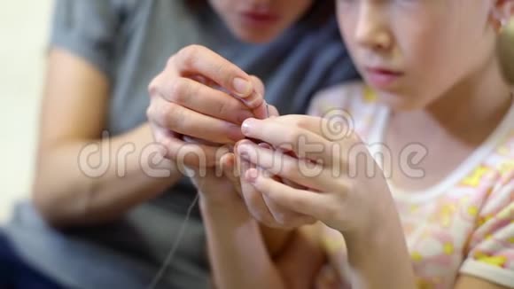 妈妈用针线来教她的女儿妈妈和她的小女儿为一个娃娃缝衣服一个女人视频的预览图