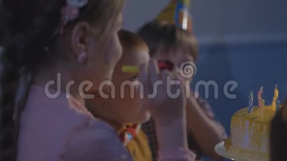 小孩子拿着蛋糕坐在红桌旁生日聚会上的孩子们快乐视频的预览图